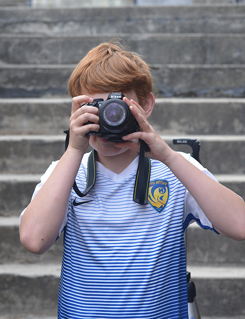 A young photographer holding a camera horizontally.