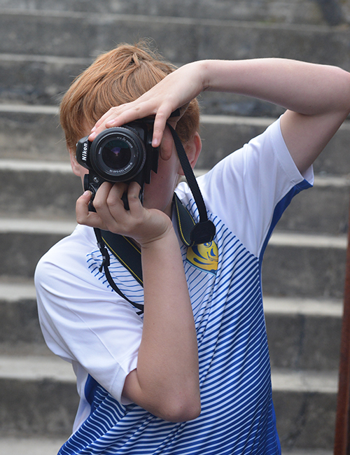 A young photographer holding a camera vertically.