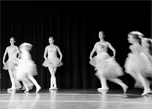 An example of Blurred Motion. Young dancers running across a stage appear blurred.